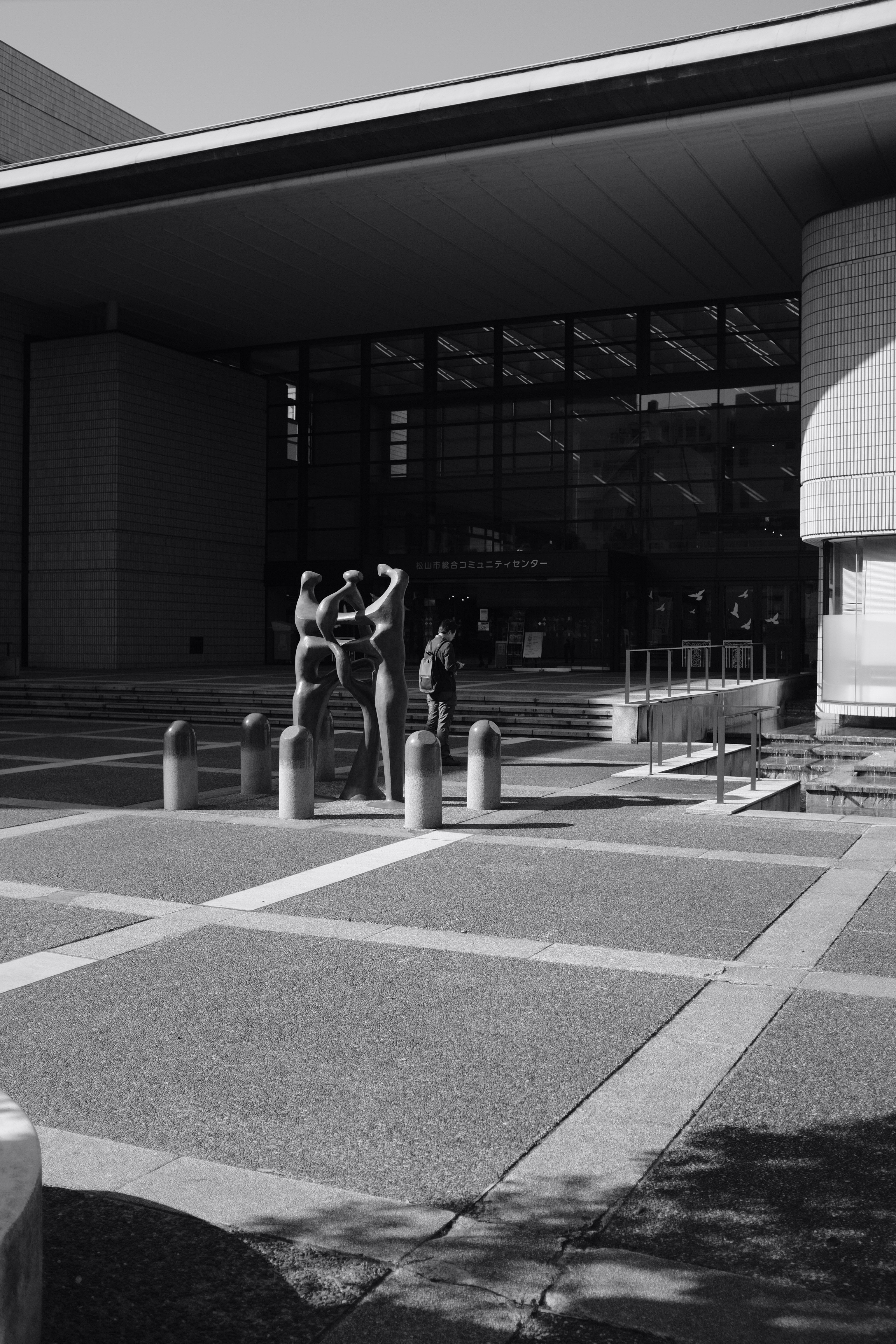 grayscale photography of person standing near building